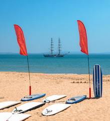 Standup Paddle boards on beach with bokeh caravel in background