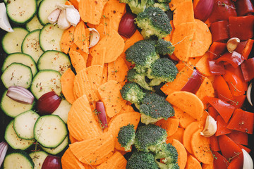Trays of fresh different vegetables ready to roast. Zucchini, sweet potatoes, carrots, broccoli, red bell vegetables
