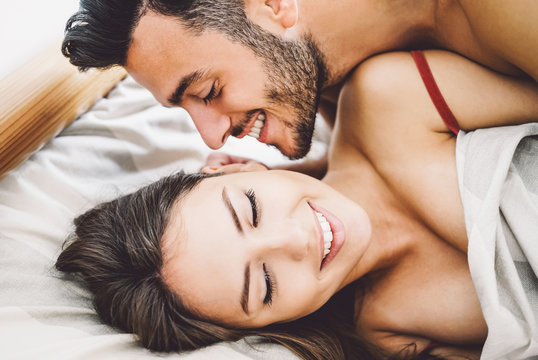 Happy romantic couple having sex - Young lovers during foreplay having tender and intimate moments in the bed - People, sexual, love and relationship concept