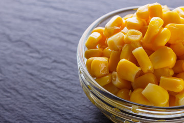 canned corn in a glass bowl on a dark stone background