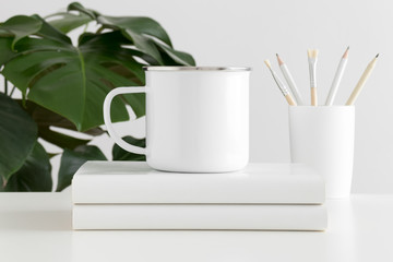 Enamel mug mockup with workspace accessories and a monstera plant.