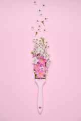 Paintbrush With Blossoms and pink flowers on pink background. Flat lay, top view, copy space