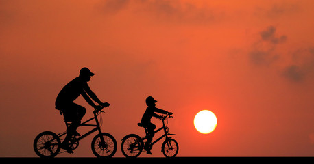 Fototapeta premium silhouette Father and son riding bicycle at sunset sky