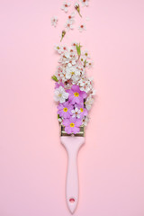Flowers composition. Paintbrush With Blossoms and Purple flowers on pink background. Flat lay, top view, copy space