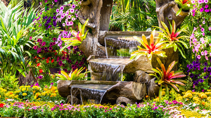 Panele Szklane  Wodospad płynie i żywa ozdoba doniczek w przytulnym przydomowym ogrodzie kwiatowym na lato.