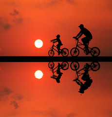 Obraz premium silhouette Father and son riding bicycle at sunset sky