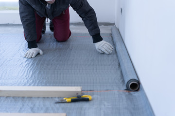 master carpenter mounts pine wood floor - eco-friendly flooring. gluing the insulation layer under...