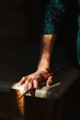 Hand o artist with a brush. Sun rays fall on table and hand