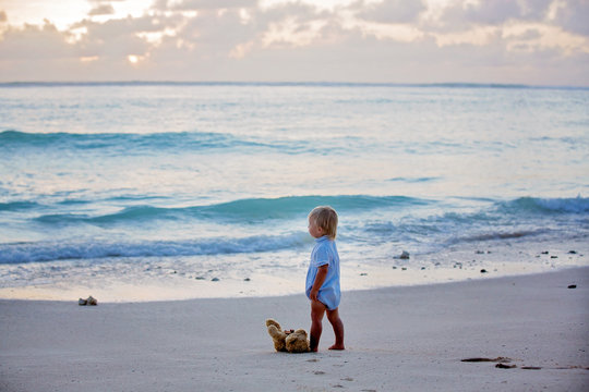 Happy beautiful fashion kid, child, casually dressed, enjoying the sunrise on the beach in Mauritius