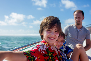 Fototapeta premium Happy beautiful fashion family, children and parents, dressed in hawaiian shirts, enjoying day trip with speed boat