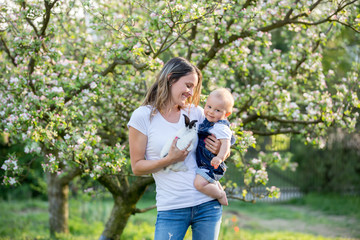 Happy mom, holding her cute baby boy in spring park