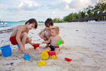 Obraz premium Cute baby boy playing with beach toys on tropical beach