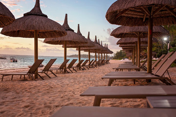 Luxury beach with beach chairs, umbrellas on beautiful  sunrise on the east coast