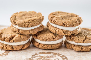 A stack of round baked gingerbread cookies with a white creamy filling