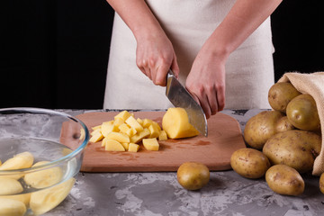 young woman in an apron cuts potatoes