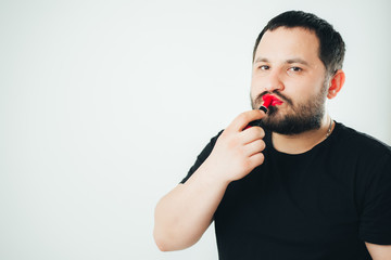 a man paints his lips with lipstick