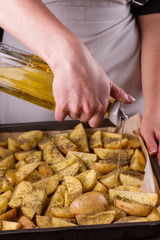 young woman in apron seasoning oil potatoes