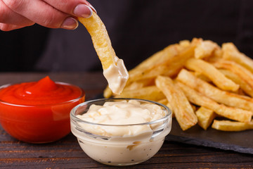 young woman dip french fries to mayonnaise sauce