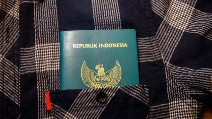 a indonesian passport in a front pocket of plaid shirt - Image