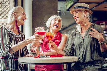 Joyful aged women drinking tasty cocktails together