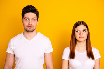 Fototapeta premium Close up photo two amazing beautiful she her he him his couple standing side by side look each other not smile tell talk speak say wear casual white t-shirts outfit clothes isolated yellow background