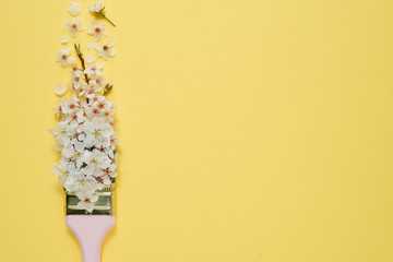 Flowers composition. Paintbrush With Blossoms on pastel yellow background. Minimal nature concept. Flat lay, top view, copy space
