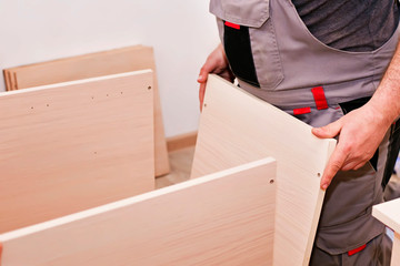 Handyman service in the process of assembling furniture. Assembly kitchen closets and cabinets from wood and chipboard particles. Home woodworks - fixing with a cordless screwdriver and mounting