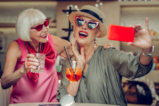Delighted positive woman taking a selfie with her friend