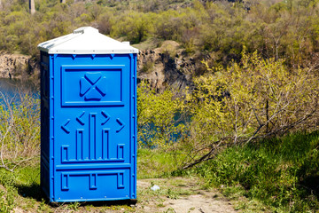 Blue Cabine Of Bio Toilet In Mountain Park at sunny Summer Day.