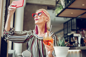 Joyful happy senior woman sitting with a cocktail