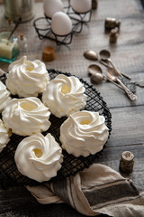 Homemade white mini meringue desserts pavlova on Wicker metal stand on grey wooden table 