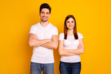 Close up photo beautiful cheer she her he him his pair stand side teamwork self-confident professionals specialists work job reliable workers wear casual white t-shirts isolated yellow background