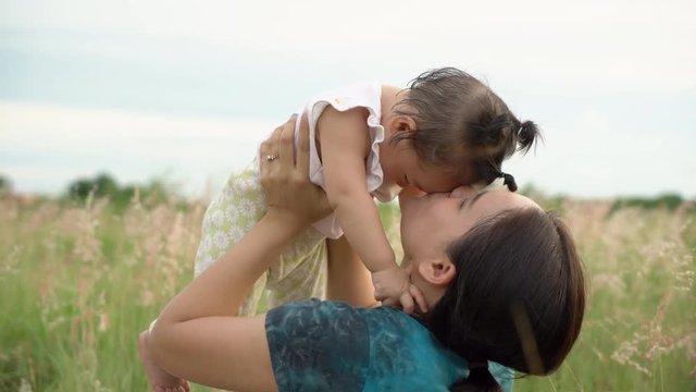 Asian young mother and daughter in the grass field at sunset.