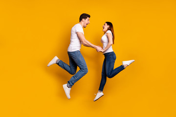 Fototapeta na wymiar Full length side profile body size photo funky crazy she her he him his pair touch arms jumping high yell scream shout best buddies wear casual jeans denim white t-shirts isolated yellow background
