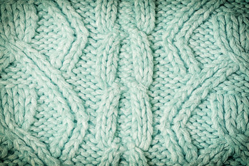 Knitted texture with patterns close-up. Blank turquoise background for layouts. Photo with vignette.