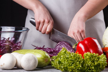 a young woman in a gray apron cuts red cabbage