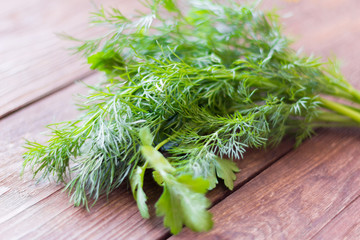 a bunch of green dill and parsley lying on a wooden background