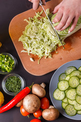 A young woman in a gray apron cuts chinese cabbage
