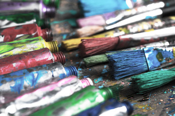 Fototapeta premium Stained paintbrushes and acrylic pain tubes on artist table. Artistic background