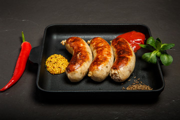 square pan with three sausages and mustard