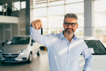 man holding car keys in car showroom