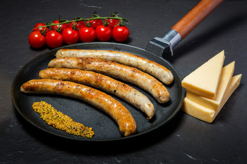 handmade fried thin sausages and mustard on frying pan