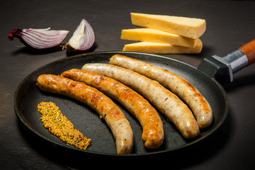 black pan with fried thin sausages and granular mustard