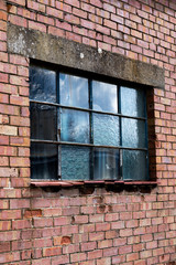 Dilapidated metal casement window frame on condemned derelict factory building awaiting demolition 