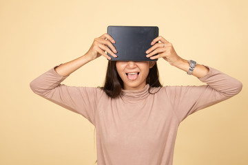 Young Asian woman with a computer tablet over her face.