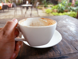 close-up coffee cup on wood table in coffee cafe.