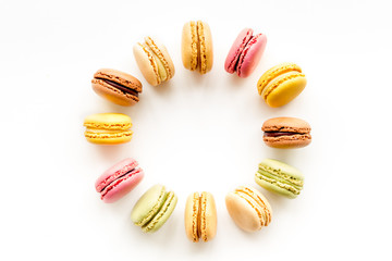 Brignt macarons for sweet break on white background top view frame