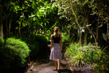 woman walking in a park with tropical trees at night