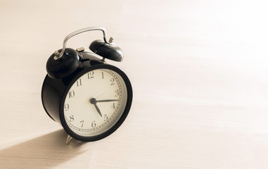Black vintage alarm clock on the floor with color background 