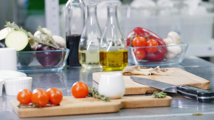 A chef working in the kitchen. A workplace table. Tomatos on the desk